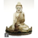 A 20th Century Indian alabaster Buddha, carved and heightened in gilt and pigment, seated in