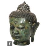 A Tibetan or Burmese cast metal figure of a Shakyamuni Buddha head with downcast eyes and