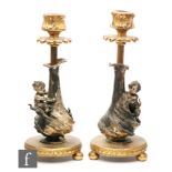A pair of early 20th Century French gilt and plated candlesticks, the sticks modelled in the