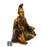 A Chinese/Tibetan figure of an Arhat, the polished copper alloy figure, in seated position wearing