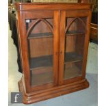 A 19th Century and later mahogany cabinet, with glazed double arched doors over a stepped plinth