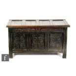 An 18th Century carved oak coffer, the quadruple fielded panel top over a scroll frieze on stiles,