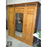 A Victorian maple veneered triple wardrobe enclosed by a paneled and mirrored door with central
