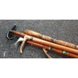 A Japanese bamboo walking stick carved with warriors, another with and aluminium pick axe handle and