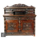 A Victorian carved dark oak sideboard, the superstructure fitted with four drawers surrounding a