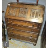 A 17th Century style oak bureau the interior enclosed by a linen fold fall over four long