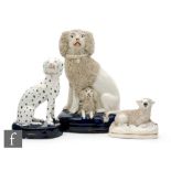 A 19th Century Staffordshire figure group of a poodle with a puppy seated to a domed blue cushion