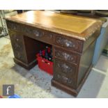 A Victorian oak kneehole pedestal desk fitted with three lion mask handle frieze drawers and three