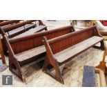 A pair of stained pine pews each with a panelled back on shaped ends, height 88cm x width 67cm x