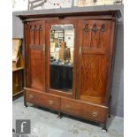 An Arts and Crafts mahogany triple door compactum wardrobe, the cornice pediment above pilaster