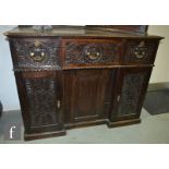 A Victorian carved oak sideboard fitted with three frieze drawers over a recessed cupboard with lion