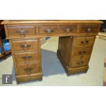 An early 20th Century oak kneehole pedestal desk, the leather inset top over three frieze drawers