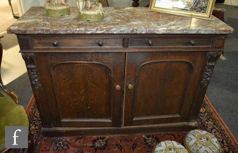 A Victorian carved dark oak two door sideboard on a plinth base, with brown veined marble top,