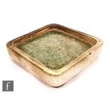 A post war stoneware dish of rounded square section in oatmeal glaze with crackle glass to the