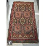 A Kashan style rug with guls and geometric medallions on a deep red ground within multi running