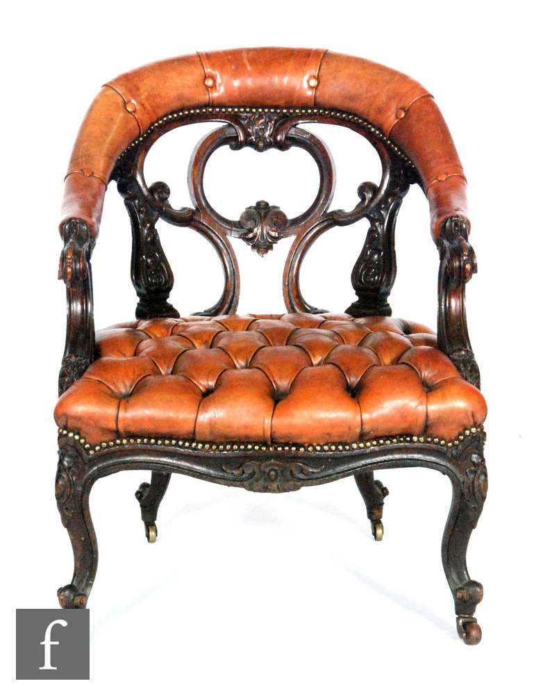 A Victorian carved oak tub shaped easy chair with pierced scroll back, on cabriole legs to the front