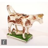 A 19th Century Staffordshire cow creamer raised to a rectangular plinth, the cow with brown