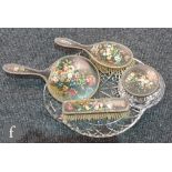 A four piece silver gilt and later painted floral dressing table set decorated with urns of