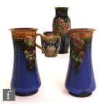 A pair of early 20th Century Royal Doulton vases of footed waisted form with flared rim, each