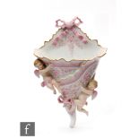 A late 19th Century continental hard paste porcelain wall pocket modelled as folded fabric with pink