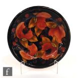 A Moorcroft shallow plate decorated in the Pomegranate pattern with open and whole fruit and berries