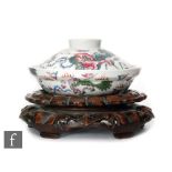 A Chinese famille rose Shishi lidded dish of stepped circular form, surmounted by a domed cover, the
