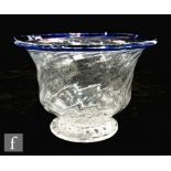 An 18th Century footed bowl of high sided flared form, wrythen moulded and with applied blue rim,