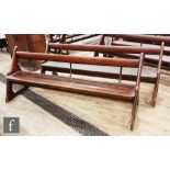 A pair of pine pews with iron supports on shaped ends, height 88cm x depth 67cm x length 225cm. (2)