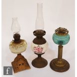 A collection of three early 20th Century oil lamps, to include a porcelain example painted with