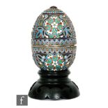 A Russian silver and cloisonne enamelled Easter egg decorated in tonal red, green and blue foliate