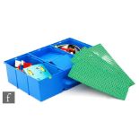 A collection of assorted Lego pieces in a storage case topped with three base boards, with