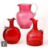 A group of three late 19th Century ruby glass jugs, all with applied clear handles, including a