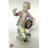 A 19th Century model of a boy sat upon a rocky pedestal holding a hat full of apples, all to a