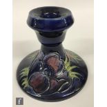 A Moorcroft piano candlestick decorated in the Anemone pattern with crimson and purple flower