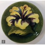 A Moorcroft pin dish coaster decorated in the Hibiscus pattern with a yellow and purple flower