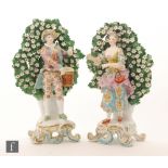 A pair of early 20th Century continental figures of a lady and gentleman stood before a floral