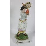 An attractive 18th Century earthenware glazed and painted Figure of a young Woman with tambourine