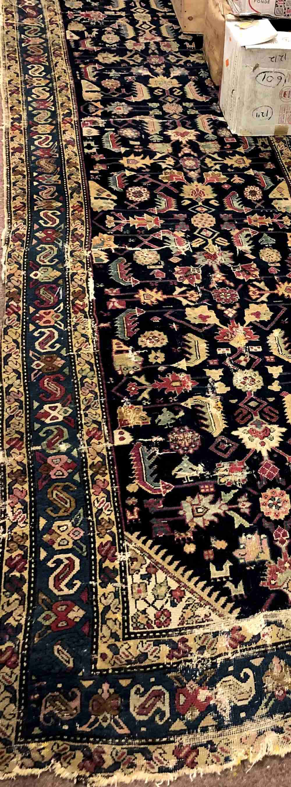A large antique Oriental Runner, the dark blue ground centre with multiple designs,
