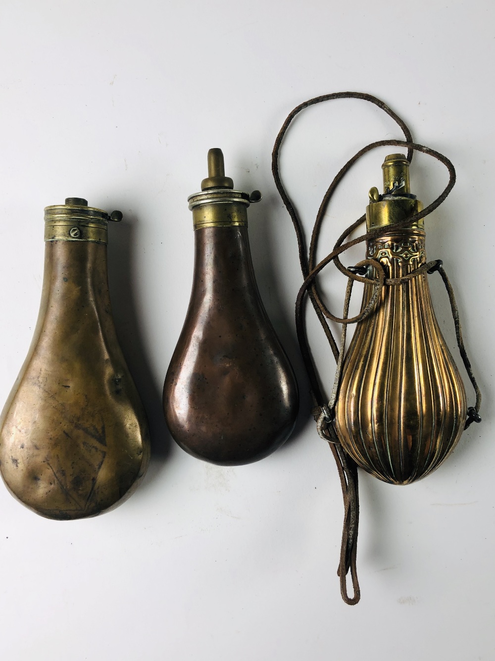 Three antique copper Powder Flasks, two plain and one engraved.