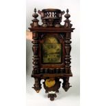 A walnut carved Vienna Wall Wagger, with small arched brass face and brass pendulum,