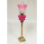 A tall antique brass Corinthian style Table Lamp, with crimson glass bowl, plain glass globe,