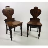 A pair of attractive Victorian mahogany shield shaped armorial Hall Chairs, on turned front legs.