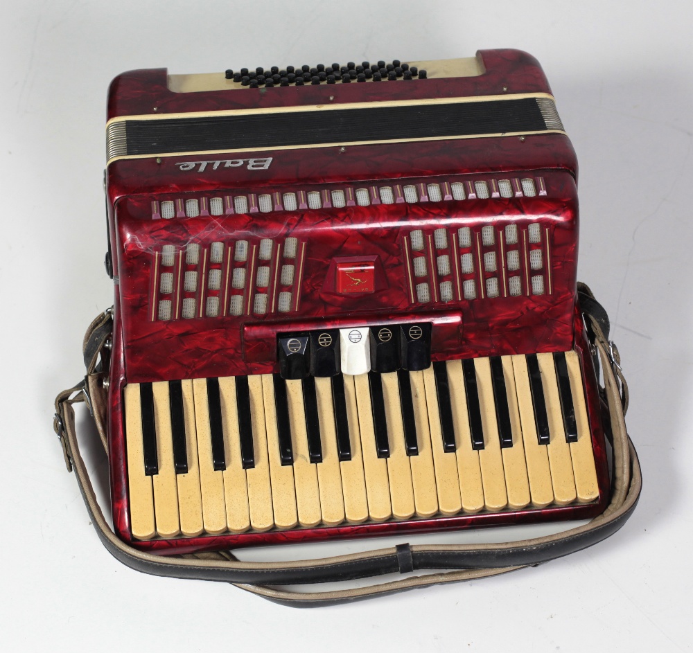 A "Boule" piano Accordion, red marble effect with leather straps, in original case.