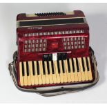 A "Boule" piano Accordion, red marble effect with leather straps, in original case.