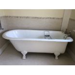 A Victorian cast iron deep bath with brass taps, supported on four lion paw feet.