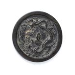 A small Chinese circular bronze hand Mirror, inscribed and with dragon in relief, 4 1/4" (10cms).