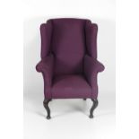 A Georgian style winged back Armchair, covered in purple fabric, on cabriole legs.