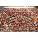 A fine 20th Century Middle Eastern red ground Carpet, with central diamond design and floral border,