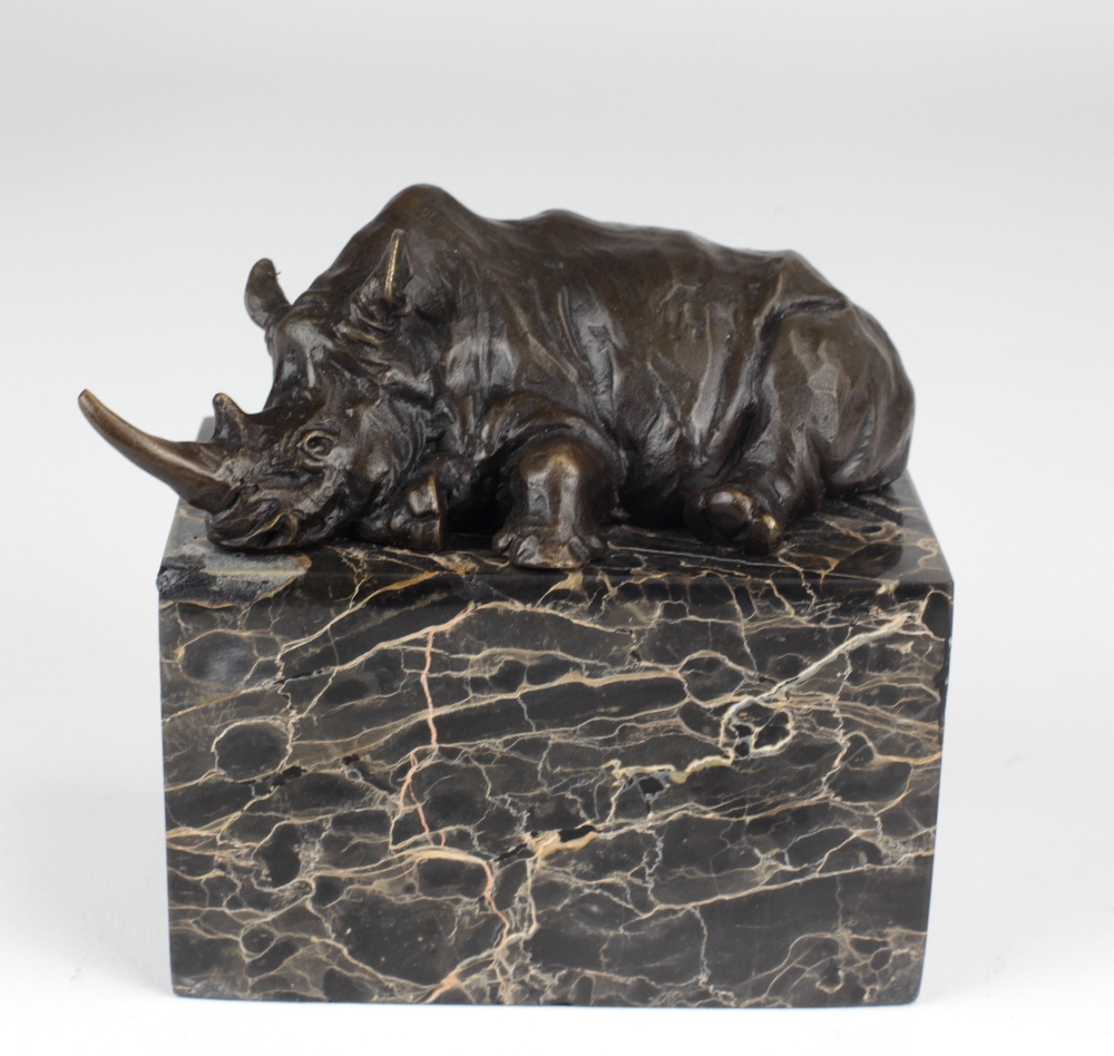 An attractive bronze figure of a reclining Rhinoceros, on rectangular dark veined marble base,