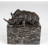 An attractive bronze figure of a reclining Rhinoceros, on rectangular dark veined marble base,